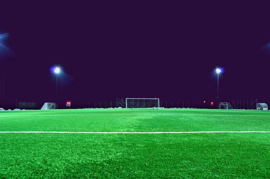 Footballs on an artificial turf pitch at night under floodlights